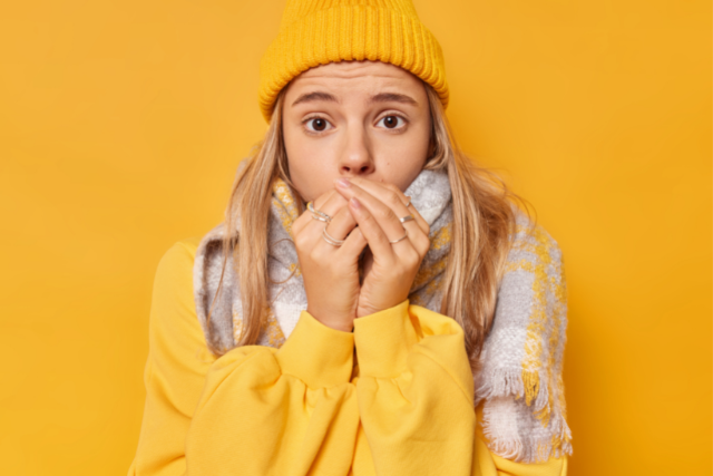 ragazza con cappello e sciarpa che riscalda le mani